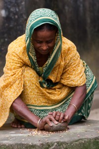A woman in Bangladesh grinds maize to prepare food for her family